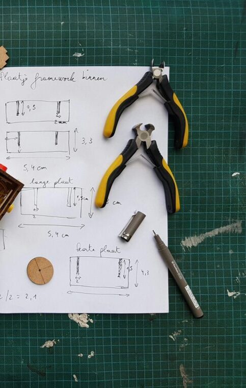Overhead view of DIY electronics project with components and tools on grid mat.